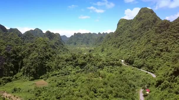 鸟瞰绿色的乡村峡谷和蜿蜒的现代公路 在阳光明媚的高地附近的丘陵 — 图库视频影像