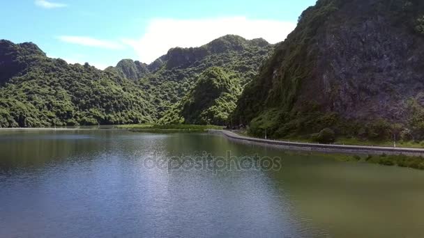 无人驾驶飞机在靠近小山脚下的柏油马路和海湾表面的云彩阴影附近移动到画报绿岛 — 图库视频影像