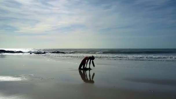 小女孩与马尾辫剪影在瑜伽姿势反对变化的背景从海洋反射上升的太阳到海滩 — 图库视频影像