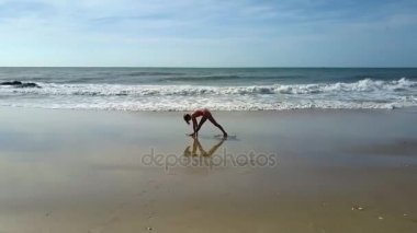 Havadan görünümü masmavi okyanus dalgaları ıslak kum kız mavi gökyüzü altında sahilde spor egzersizleri değiştirme için rulo