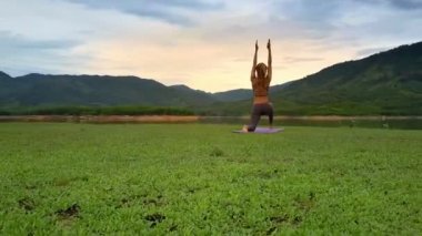 arka yoga poz eller yukarı tepeler karşı resimsel Gölü ile uzun at kuyruğu standları ile güzel kız göster