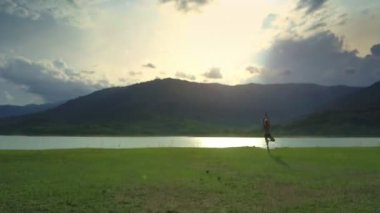 yoga konumunda güneş yansıma göl yüzeyi Vrikshasana yaparken kadın siluet üzerinde casus uçak uçar