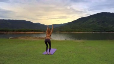 ince kız geri yoga poz Tadasana yakın göl gri gökyüzü altında dağlık manzara karşı bükme dron gösterir
