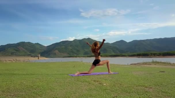 Flycam Mueve Rubia Delgada Mujer Haciendo Ejercicio Yoga Con Las — Vídeos de Stock