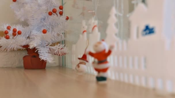 特写白色小人造圣诞树 上面装饰着红色浆果和圣诞老人 桌子上堆着雪人 — 图库视频影像