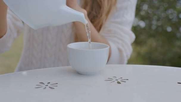 特写妇女倾吐茶入杯子坐在桌上用漂亮的白色桌布在餐馆里 — 图库视频影像