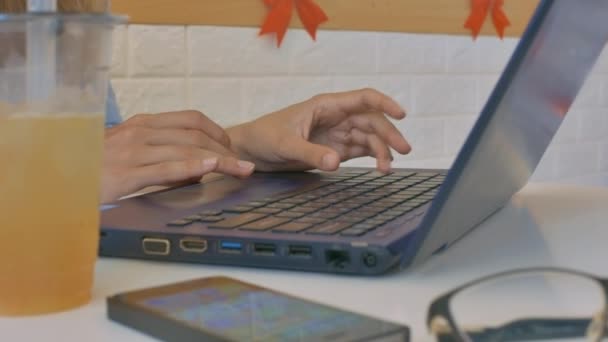大きなプラスチック ガラス コンピューターのバック グラウンドでタイプの女の子の手によってスマート フォンでマクロ冷たい新鮮なジュース — ストック動画