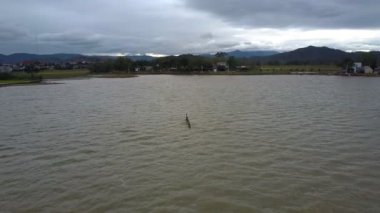 Sığınağın Kano hill siluetleri ve bulutlu gökyüzü karşı hava panorama sınırsız gri göl ve yerel adam duruyor