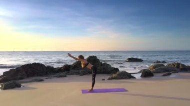 Mavi gökyüzü karşı sahilde Yoga vücut fantastik panorama ince kız at kuyruğu siyah tayt ve üst ile eğiliyor