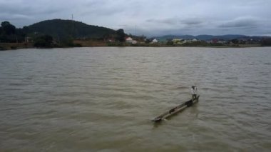 Göl alt Köyü karşı sopayla kapalı hava görünümünü yerel adam beyaz gömlek ve şapka sığınağın kanoya sahanın iter