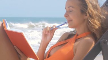 yan görünümü mayo mutlu güzel kızı rüyalar ve notlar dalgalar çalıştıran karşı sahilde kitap yapar