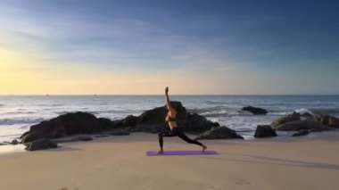 ince sarışın uzun saçlı kız okyanus kayalar ve sınırsız mavi gökyüzü karşı boş sabah sahilde yoga uygulamaları