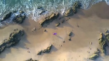 harika hava panorama köpüklü şeffaf dalgalar taşlar üzerinde rulo ve kız küçük rakam mindere yalan ile plaj kum