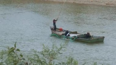 Yerel halkın nehir uzun yeşil borular kullanarak gelen bina kum boşaltma flatboat üzerinde çalışmak ve tekne içine kum Ekskavatör