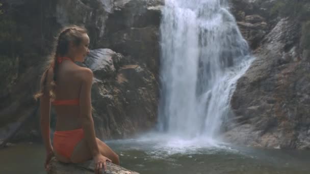 クローズ アップ サイドビュー笑顔長い髪の女の子を楽しんで実行している美しい滝に対する絵の性質 — ストック動画