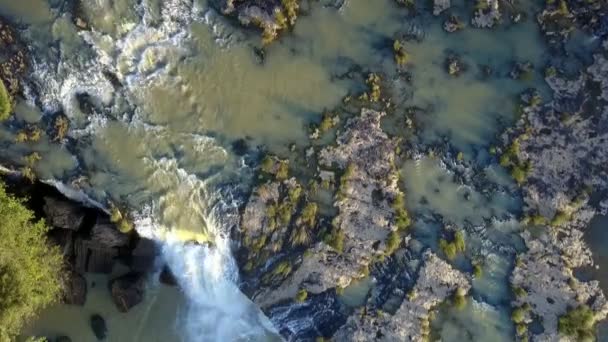 belle vue verticale puissante chute d'eau mousseuse tombant à travers les pierres et les rapides de la rivière sous la lumière du soleil du soir 