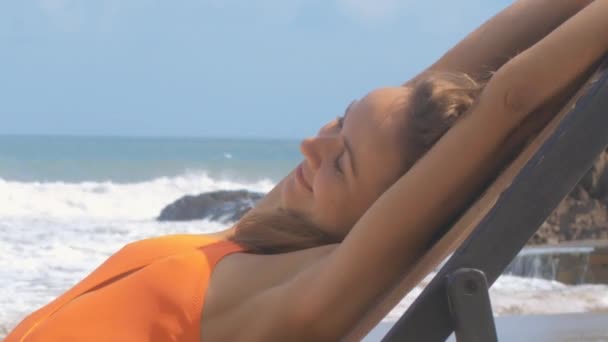 サイド ビューうれしそうな魅力的な女性ビキニ ビーチ椅子と白い泡の海の波の手を引っ張る — ストック動画