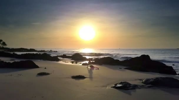 女の子が海の水面に明るい太陽ディスクの光と太陽のパスに対して砂浜にフィットネスに近づいて — ストック動画
