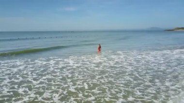 sınırsız masmavi okyanus ve mavi gökyüzü karşı kırmızı mayo ince kız harika görünümü köpüklü deniz dalga kret yıkar