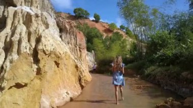 takip atış sarı uzun saçlı kadın peri akışı yüksek kayalıklarla ve tropik bitkiler arasında güzel gün geldi