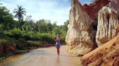 uzun saçlı sarışın ünlü peri akıntıya karşı beyaz kayalar içinde yalınayak ayak bileği derin ayakta sopayla selfie yapar