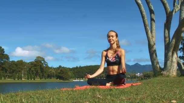 Blondes Mädchen Sitzt Yoga Pose Padmasana Auf Grünem Gras Kahlen — Stockvideo