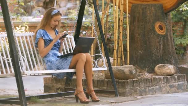 Blondes Langhaariges Mädchen Blauen Sommerkleid Sitzt Auf Schaukel Mit Laptop — Stockvideo