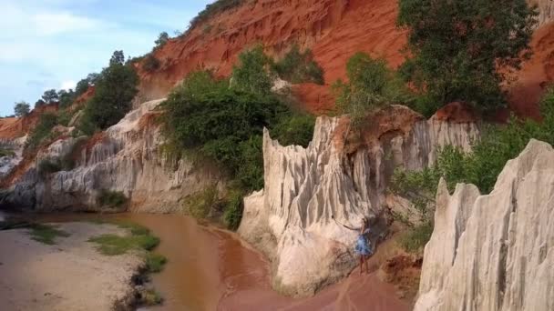vue aérienne Fée ruisseau canyon futuriste blanc roches et blond fille en robe bleue fait selfie contre les pierres 