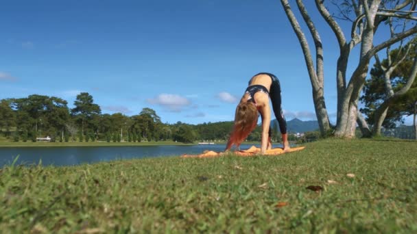 特写年轻女子瑜伽改变姿势橙色 Karemat 反对美妙的风景在蓝天下 — 图库视频影像