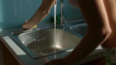closeup düzgün kız sabunlardı Lavabo Mutfak mavi duvarlı sünger kullanarak yıkama ev işi yapar