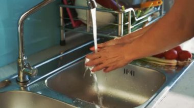 tatlı kız yıkar kırmızı lavabo üzerinde su akışı altında domates olgunlaştırmak ve mutfak plaka üzerinde koyar