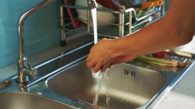 tatlı kız yıkar kırmızı lavabo üzerinde su akışı altında domates olgunlaştırmak ve mutfak plaka üzerinde koyar