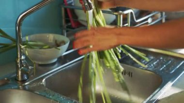 portre Bayan yıkama taze yeşil soğan grup su akışı altında eller ve mutfak lavaboda yukarıda sallar