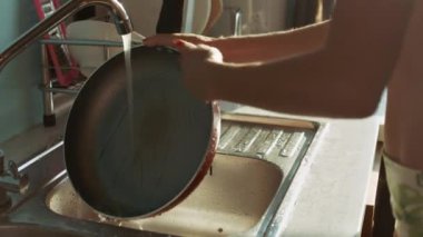 Kırmızı manikür durular kızartma tavası musluk karşı pencereden parlak güneş ışığı altında closeup kadınla