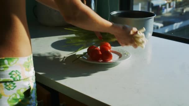クローズ アップ女性がトマトにきれいな緑のタマネギを置くやかんと Multicooker の近くの窓の向かい側 — ストック動画
