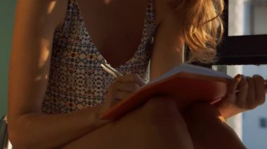 kalemle günlüğü açık pencere yazar tarafından closeup güzel kız oturur ve sarı uzun saçlı Rüzgar sallıyor