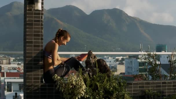 Nahaufnahme Seitenansicht Lächelndes Mädchen Entwirrt Kopfhörer Sitzt Auf Moderner Terrasse — Stockvideo