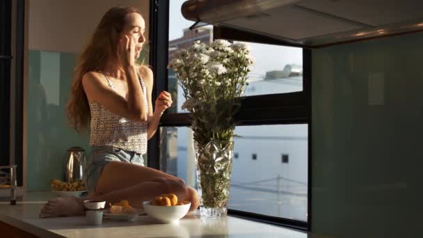 Όμορφο Κορίτσι Μακριά Ξανθά Μαλλιά Τρώει Μανταρίνια Συνεδρίαση Ευρύ Περβάζι — Αρχείο Βίντεο