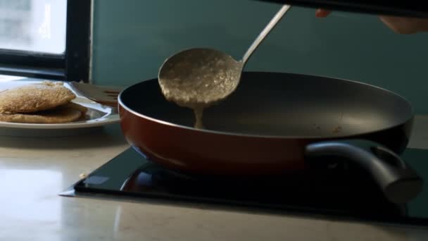 特写女孩炊具在热的大平底锅和美味的煎饼上倒入液体面团在盘子在窗口 — 图库视频影像