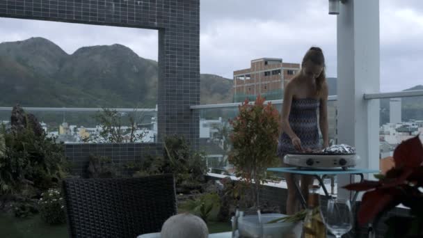 Langhaariges Mädchen Legt Fleisch Auf Elektrisches Kohlenbecken Zwischen Dachterrassenpflanzen Gegen — Stockvideo