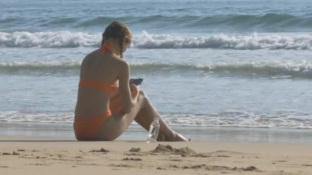 Backside View Young Slim Woman Orange Bikini Sits Looks Smartphone — Stock Video