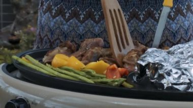 closeup kişi spatula ve kadın mavi ve gri elbise karşı elektrikli ızgara bıçak ile lezzetli domuz kaburga üzerinde döner
