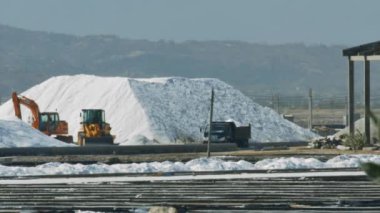 büyük deniz tuz yığın güneşli günde büyük ayıklama alanları tarafından çevrili yakınındaki ekskavatör ve kamyon çalıştırmak