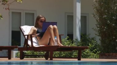 uzun saçlı kız ahşap katlanır sandalye havuzu beyaz windows bina karşı yakın oturan defter üzerinde çalışmaktadır