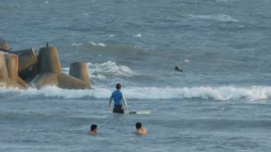 MUI KD/Vietnam - 24 Mart 2018: sörfçü binmek dalgalar üzerinde sörf tahtaları ve insanlar yüzmek beton dalgakıranlar yakınındaki köpüklü okyanus plaj tarafından 24 Mart MUI Ne içinde