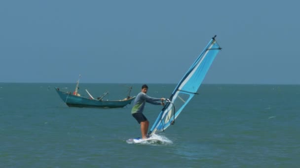 在蓝天下的无边的和平海洋中 体育男子冲浪沉迷帆和小船 — 图库视频影像