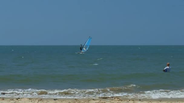 背面看秃头教练手表帆船冲浪初学者站在水附近波浪溅在海滩上 — 图库视频影像