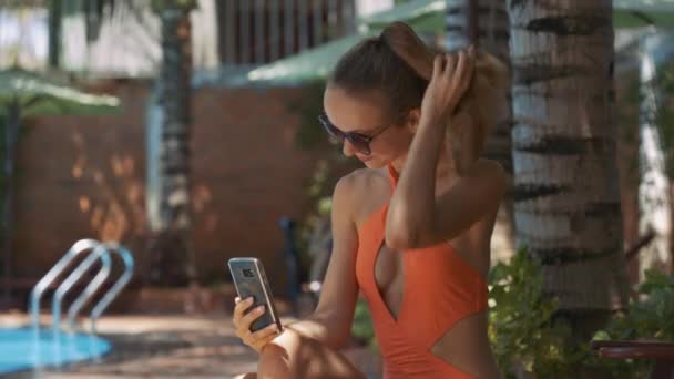 关闭视图聪明的女孩在太阳镜直剪理发拿着电话在手反对游泳池在家 — 图库视频影像