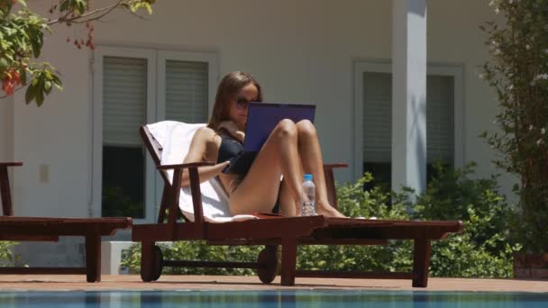 木材の寝椅子テキストが白い家に対して現代のラップトップに入力のプールの近くに位置してクローズ アップ素敵な女の子 — ストック動画