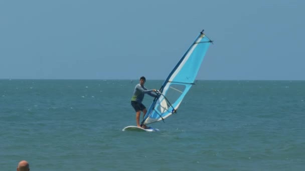 光头教练控制风帆初学者滑动冲浪板上的绿松石海洋对遥远的地平线 — 图库视频影像